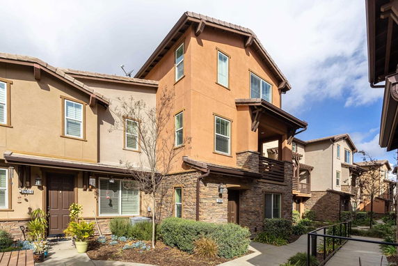 Front view of a modern, multi-story townhouse with stone and stucco exterior.