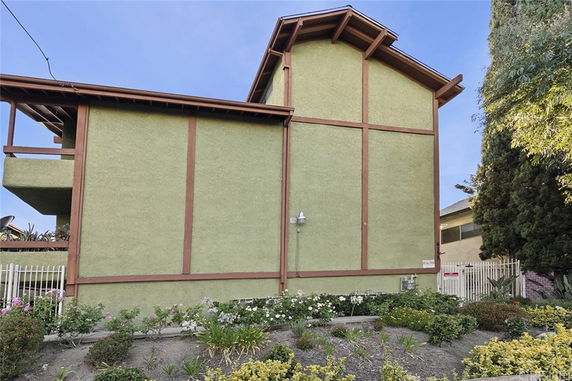 Side view of a multi-story house with a green facade and wooden trim.