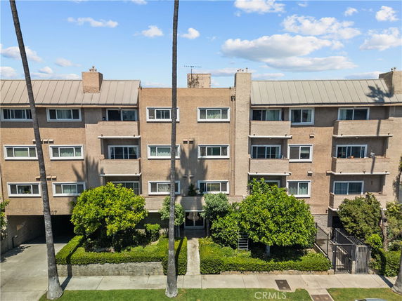 Front view of a multi-story apartment building with balconies and a gated entrance.