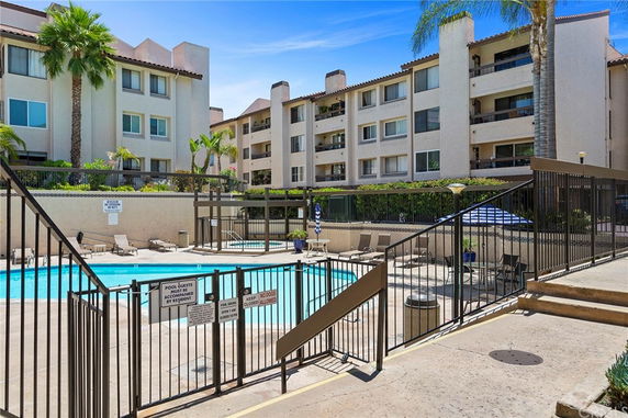 Outdoor area with a swimming pool and a multi-story building in the background.