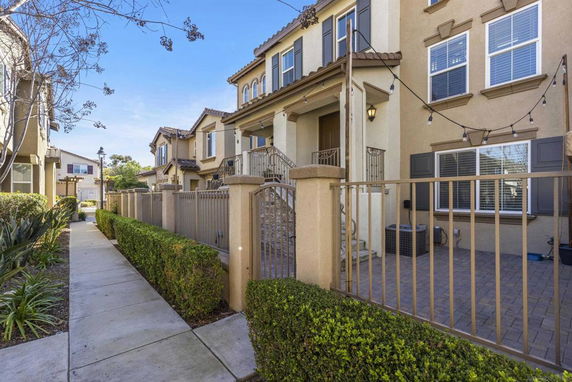 Front view of a multi-story house with a gated entry and pathway.