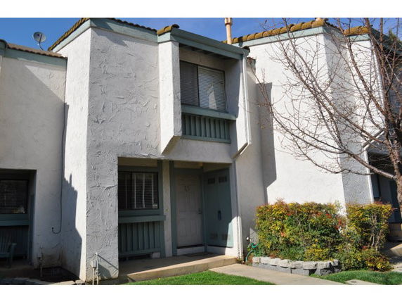 Front view of a two-story townhouse with a small balcony and stucco exterior.