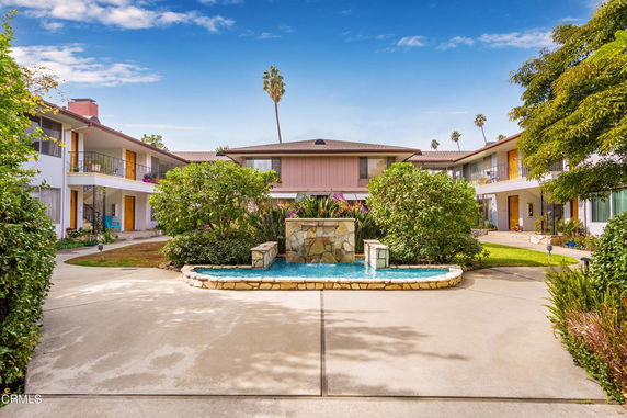 Front view of a two-story residential building with a central courtyard and fountain.