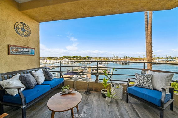 Outdoor seating area overlooking a marina with boats and distant trees.