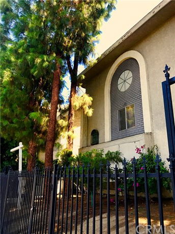 Front view of a two-story building with large arched window and trees in front.