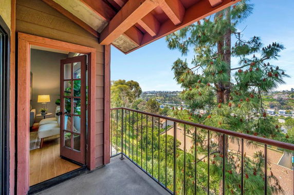 Balcony view overlooking a landscape with trees and distant buildings.