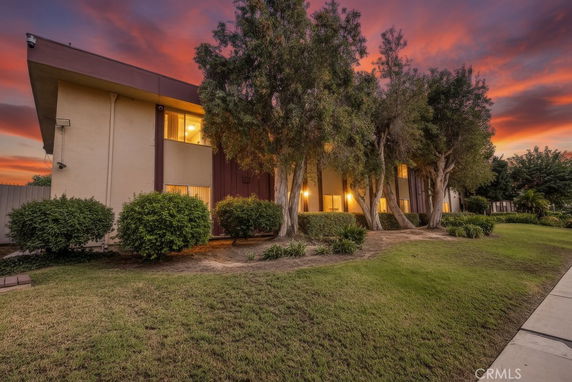 Front view of a two-story building with lighting and trees at sunset.