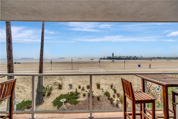 Panoramic view from a balcony overlooking a sandy beach and ocean.