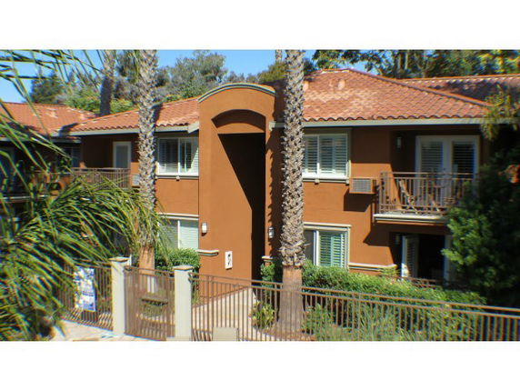 Front view of a two-story house with balconies and a tiled roof.