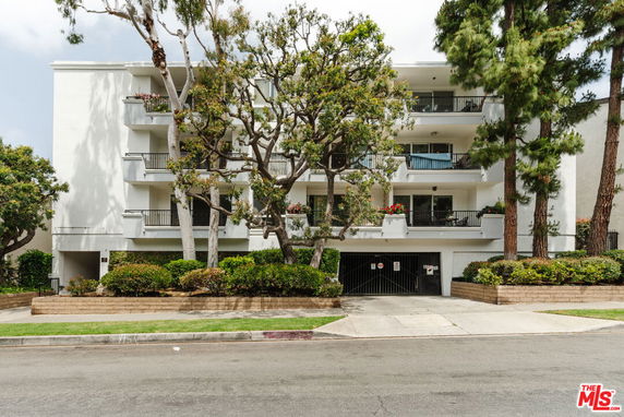 Front view of a multi-story residential building with balconies and trees.