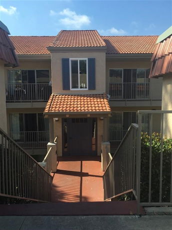 Front view of a residential building with a tiled roof and stairway entrance.