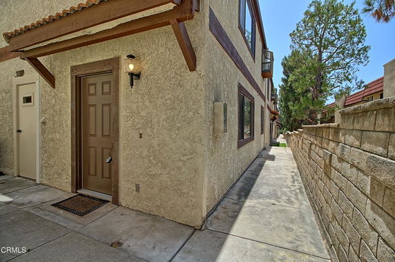 Side view of a multi-story building with a brown door and a walkway.