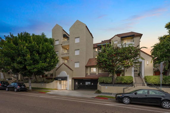 Front view of a multi-story residential building with balconies and a gated entrance.