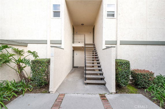 Exterior view of a building entrance with a staircase leading to an upper level.