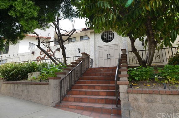 Front view of a building with a staircase leading to a large door.