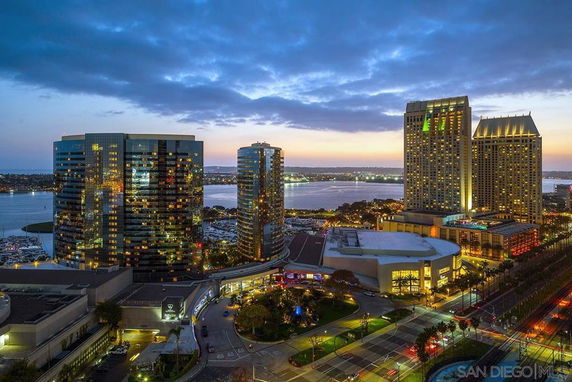 Panoramic view of a skyline with high-rise buildings near a waterfront at dusk.
