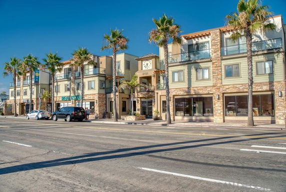 Front view of a multi-story commercial building with palm trees in front.