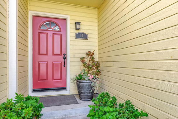 Front view of a house entrance with a red door and plant decoration.