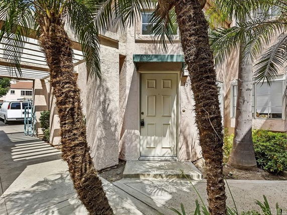 Front view of a residential building with a small porch and palm trees.