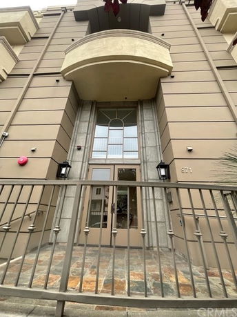 Front view of a tall building with a decorative balcony and large entrance doors.