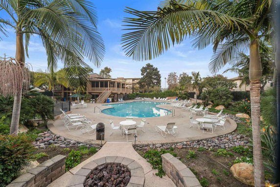 Outdoor view of a swimming pool surrounded by lounge chairs and palm trees.