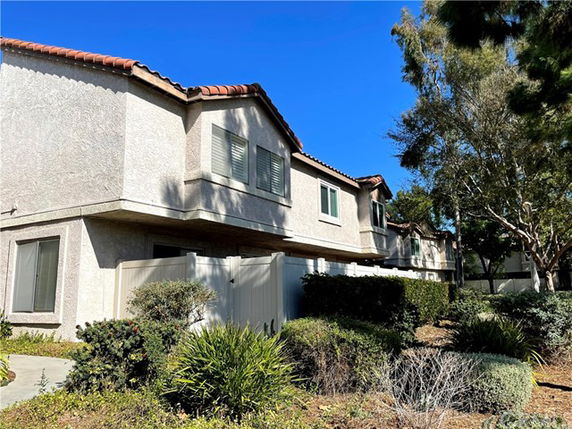 Front view of a two-story house with a white exterior and red tile roof.