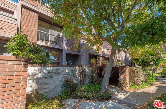 Front view of a multi-story house with brick exterior and balconies.