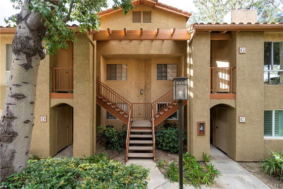 Front view of a multi-story residential building with a central staircase and arched entrances.