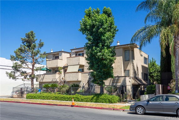 Front view of a multi-story building with balconies and stairs.