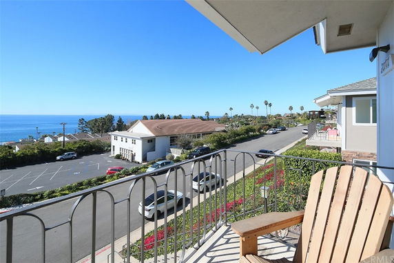 Panoramic view from a balcony overlooking the ocean and nearby buildings.