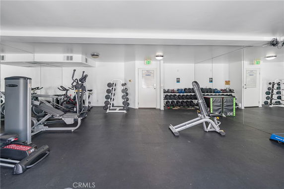 Indoor gym area with exercise equipment and weights.