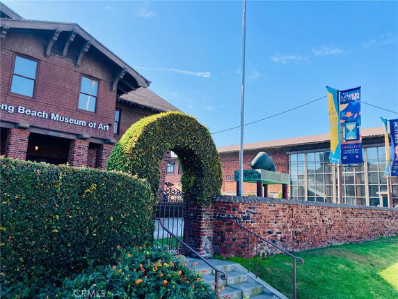 Front view of a brick building with banners and a hedge archway.