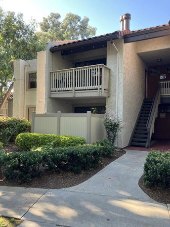 Front view of a two-story apartment building with a balcony and stairway entrance.