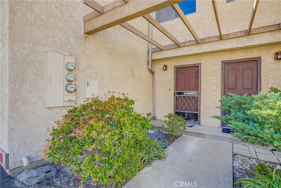 Front view of a two-door entryway with stucco walls and a pergola.