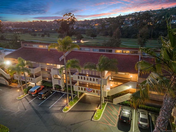 Elevated view of a multi-story building with a parking area in front.
