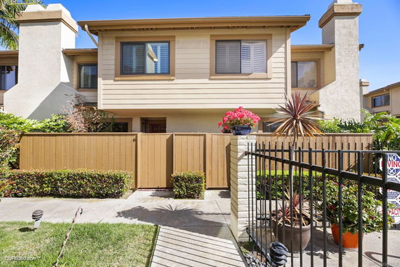 Front view of a two-story townhouse with a wooden gate and small garden.