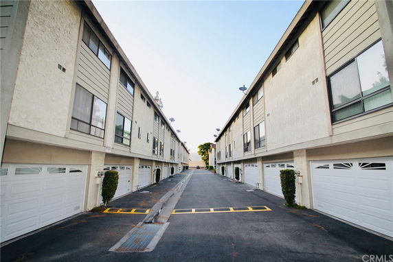 View of a parking area between two apartment buildings with garages.