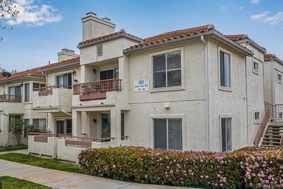 Front view of a two-story apartment building with balconies and red-tiled roof.