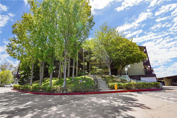 Front view of a multi-story building with trees and a staircase leading up to the entrance.
