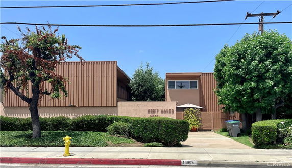 Front view of a building with a brown facade and an entrance marked by a sign reading 'Merit Manor'.