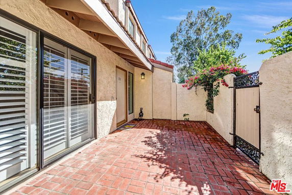 Front view of a house with a patio area and a gated entrance.