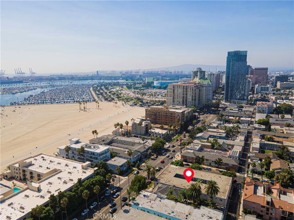 Aerial view of a coastal urban area with buildings, a beach, and a marina.