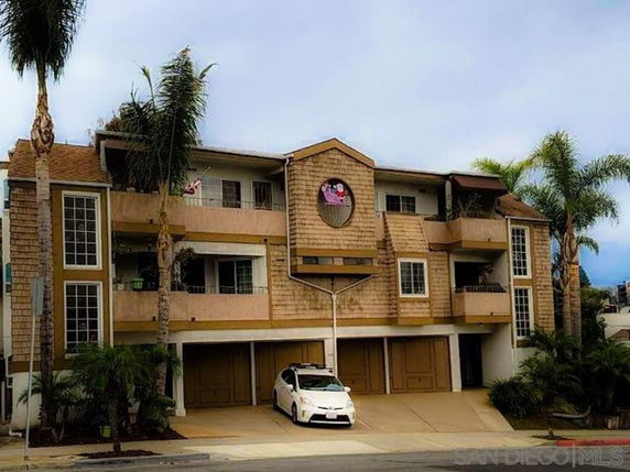 Front view of a multi-story apartment building with garages on the ground floor and balconies on the upper floors.