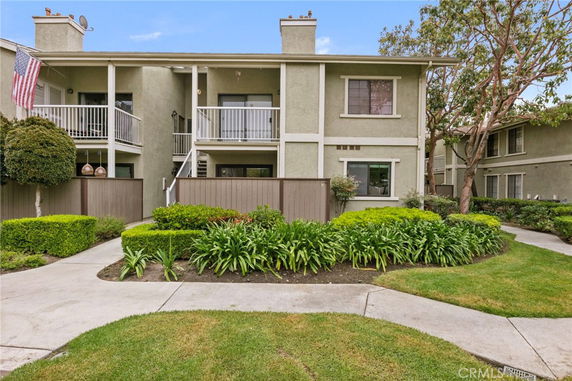 Front view of a two-story house with balconies and a garden.