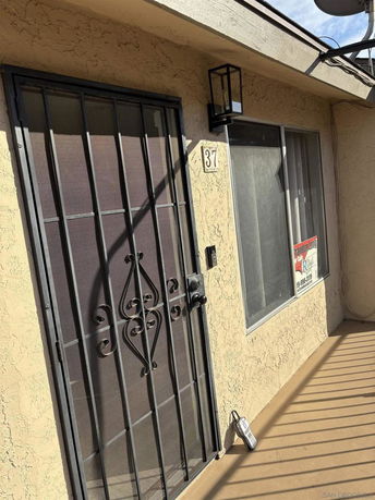 Front view of a building entrance with a metal security door and adjacent window.