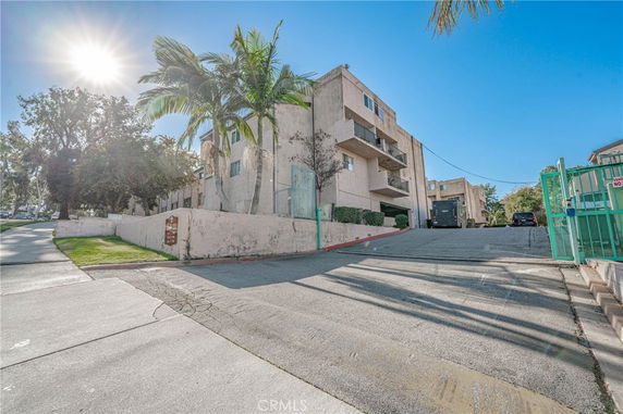 Front view of a multi-story residential building with balconies and a driveway.