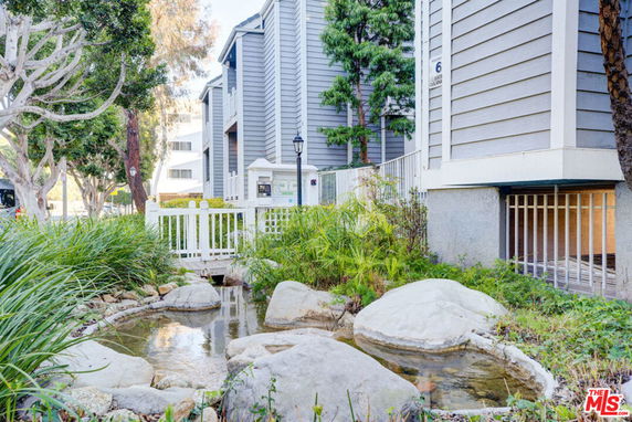Front view of a multi-story building with a small stream and landscaped surroundings.