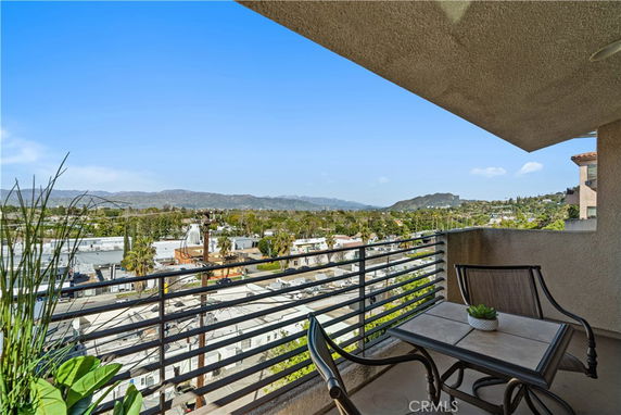 View from a balcony overlooking a landscape with buildings and distant mountains.