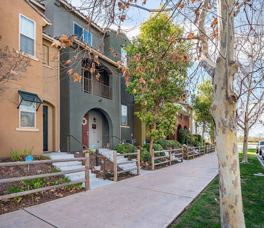 Front view of a multi-story residential building with stairs and small front gardens.