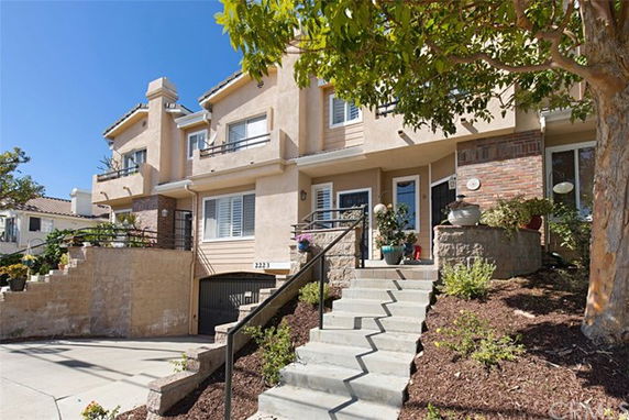 Front view of a multi-story house with a staircase leading to the entrance and an attached garage.